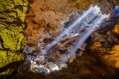 Sun rays shine through ceiling hole in Dau Go cave in Halong Bay, Vietnam